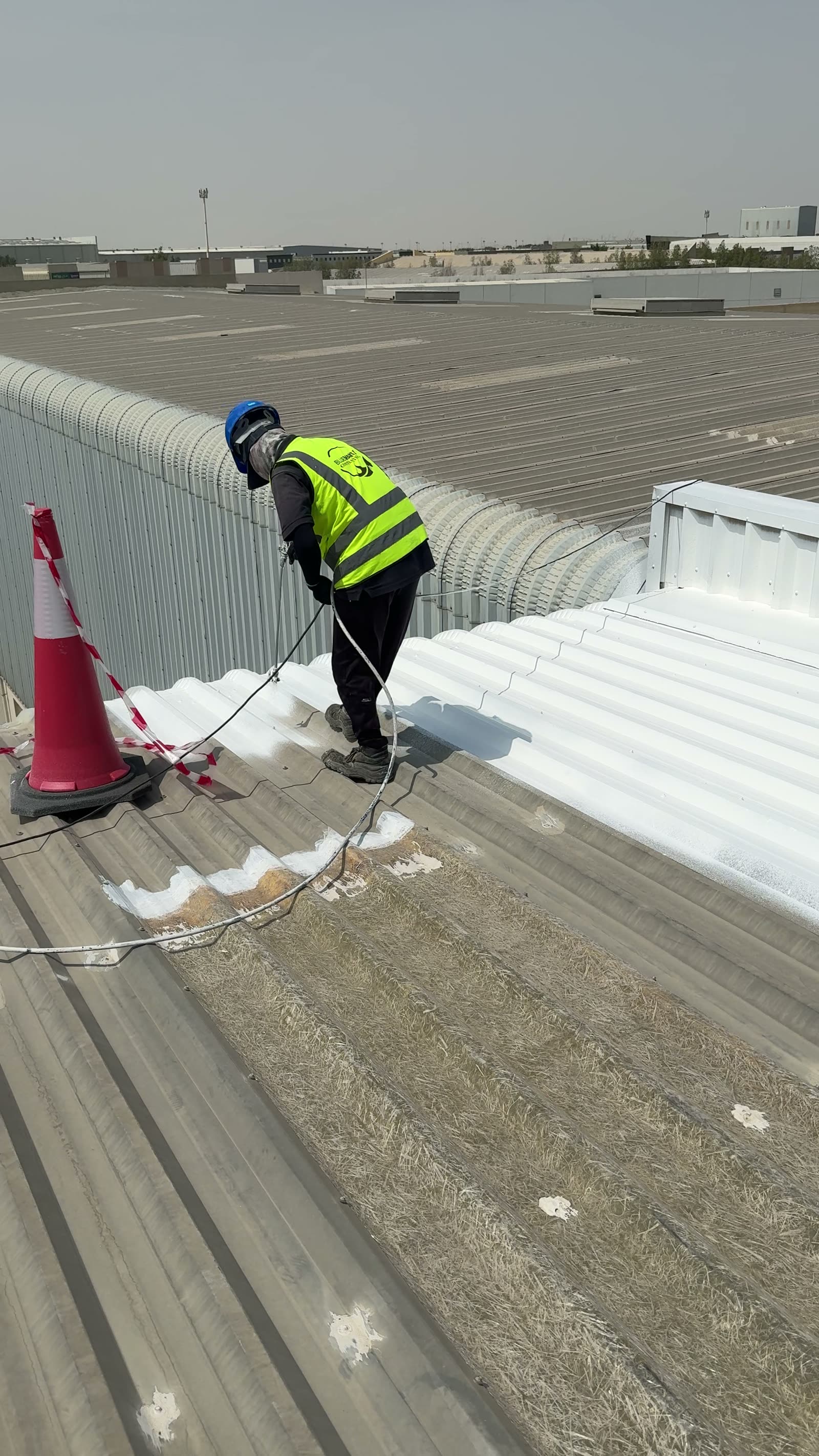 Boundary between the untreated grey metal roof and the newly coated white surface